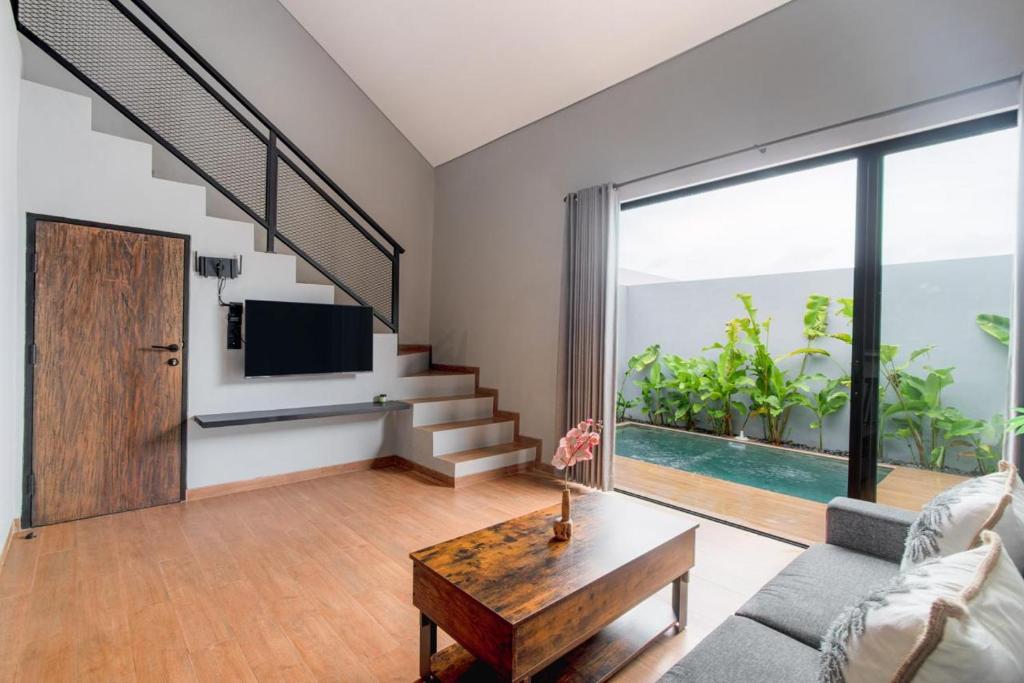a living room with a couch and a tv and a table at Iris Apartment in Dalung