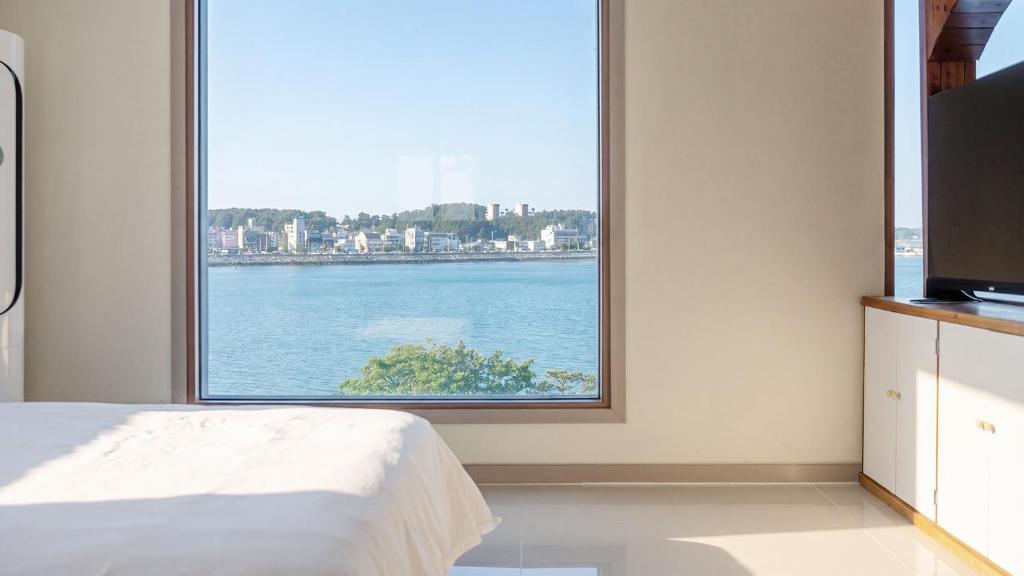 a bedroom with a large window overlooking the water at Daebudo (Yeongheungdo) Dunia Spa Pension in Incheon