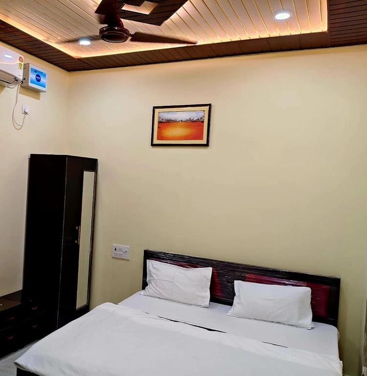 a bedroom with a bed with white sheets and a picture on the wall at Hotel Ram Shankar - Saryu Ghat in Ayodhya