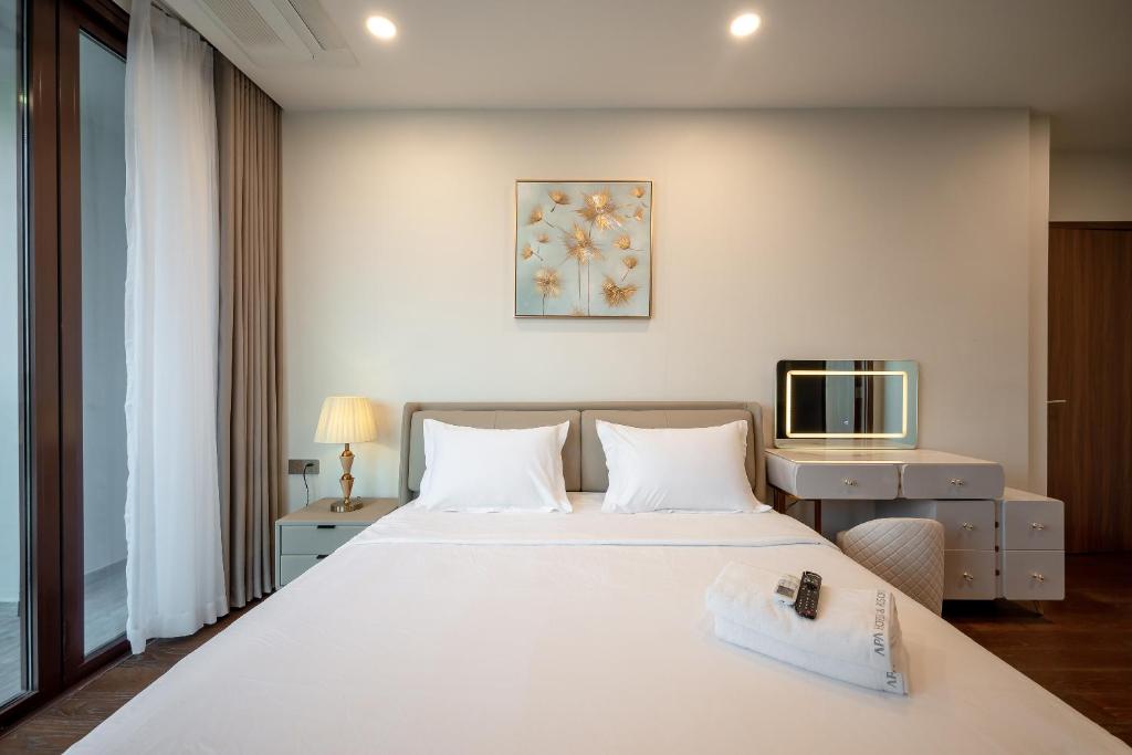 a bedroom with a large white bed and a television at Metropole Thu Thiem Condo Apartment in Ho Chi Minh City