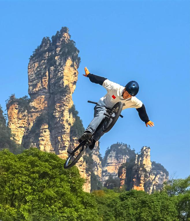 a man doing a trick on a bike in front of a mountain at Zhangjiajie Homeinn Plus Hotel-Free pick up service,Free Chinese-western Breakfast,Free Freah Coffee,Free Self-Service Laundry & Drying, Attraction Tickets Serivce in advance in Zhangjiajie