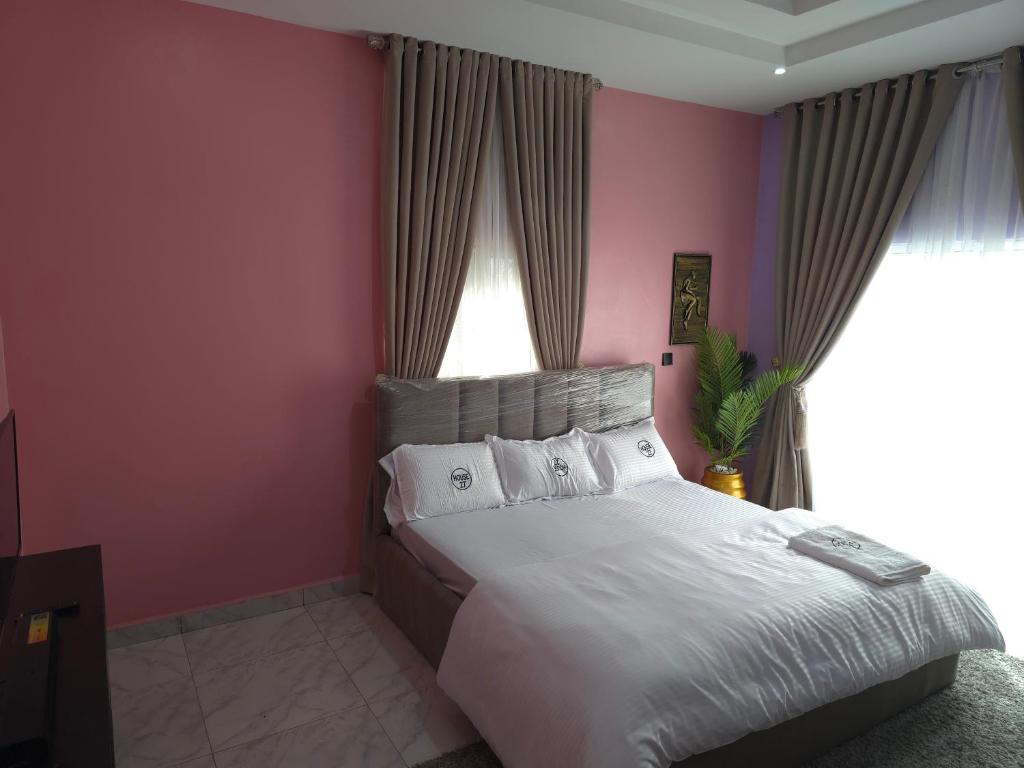 a bedroom with a bed with pink walls and a window at House 27 Cool vibes in Idu