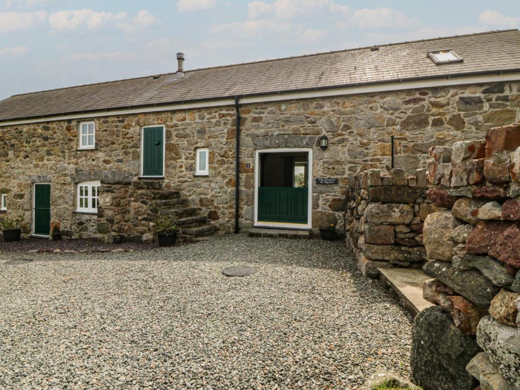a stone building with a green door and a stone wall at No 1 The Granary in Llangefni