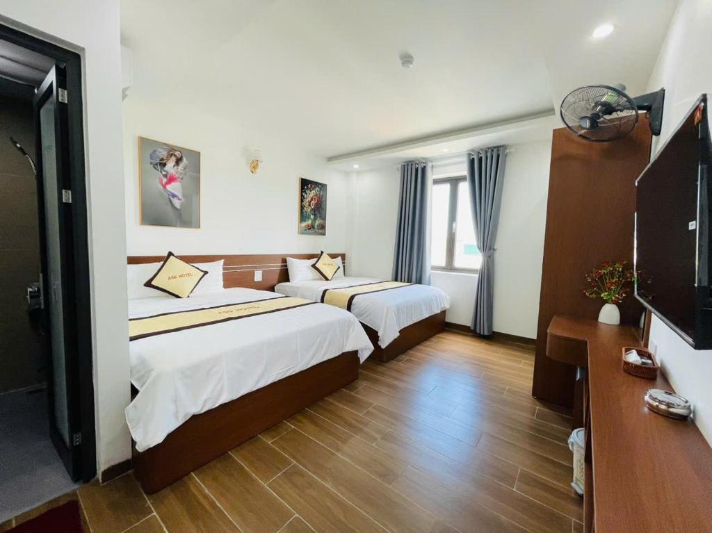a hotel room with two beds and a flat screen tv at A90 HOTEl2 in Nhật Tựu