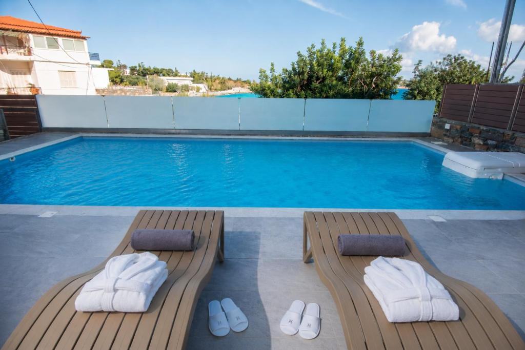 a pool with two wooden loungers and a swimming pool at Ammos Lux Apartments Crete in Agios Nikolaos