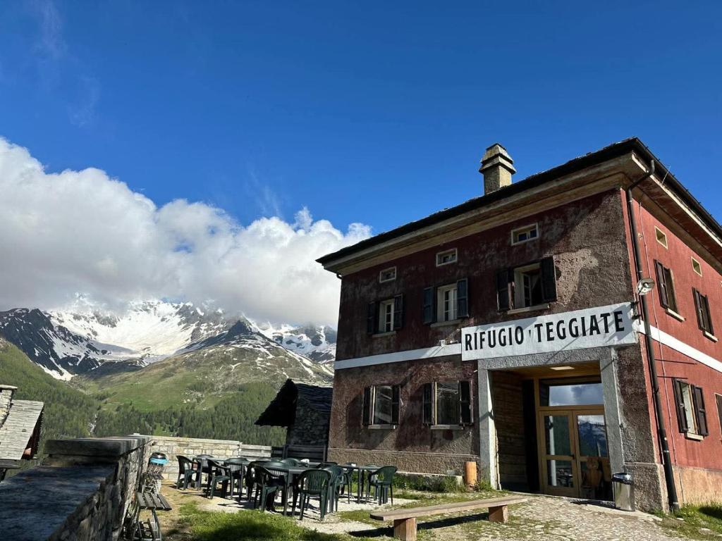 a building with tables and chairs in front of a mountain at Locanda Teggiate in Madesimo