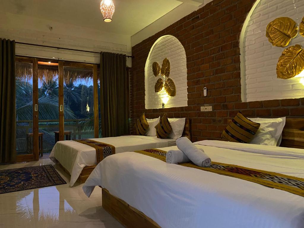 a bedroom with two beds and a brick wall at Dira Bungalows in Tetebatu