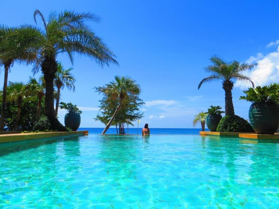 a pool with palm trees and the ocean in the background at Karon Beach Stunning 2 bed apt unit 700 in Karon Beach
