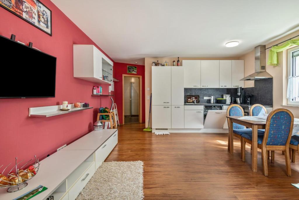 a kitchen with a red wall with a table and chairs at Ferienwohnung Kleinramspau in Regenstauf