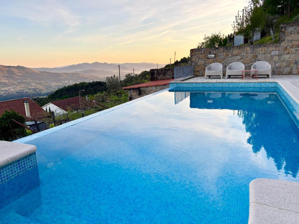 a swimming pool with two chairs and a view of the mountains at Casa Letrigo in Arcos de Valdevez
