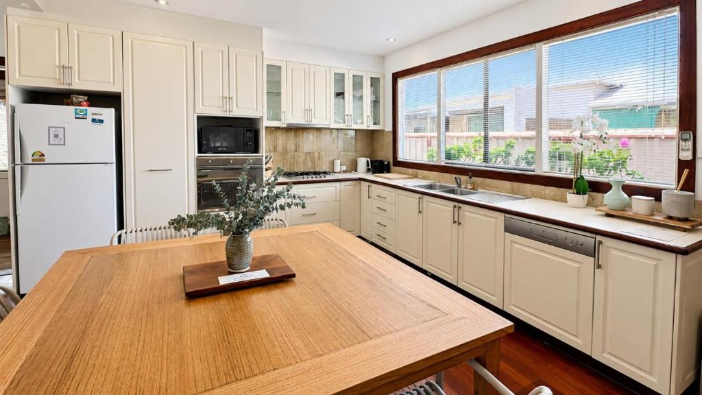 a kitchen with a wooden table and a refrigerator at Sals Cottage in Busselton