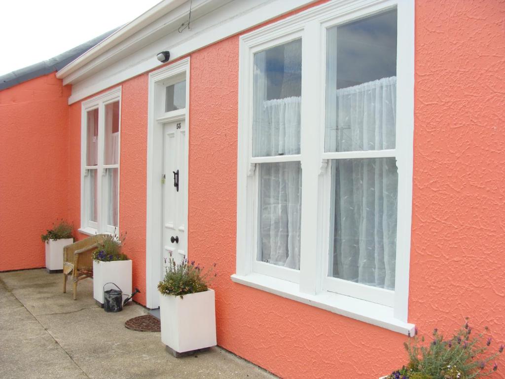 una casa roja con dos ventanas y una puerta blanca en Oamaru Pink Cottage en Oamaru