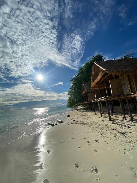 a beach with houses and footprints in the sand at Kainora Homestay in Dayang