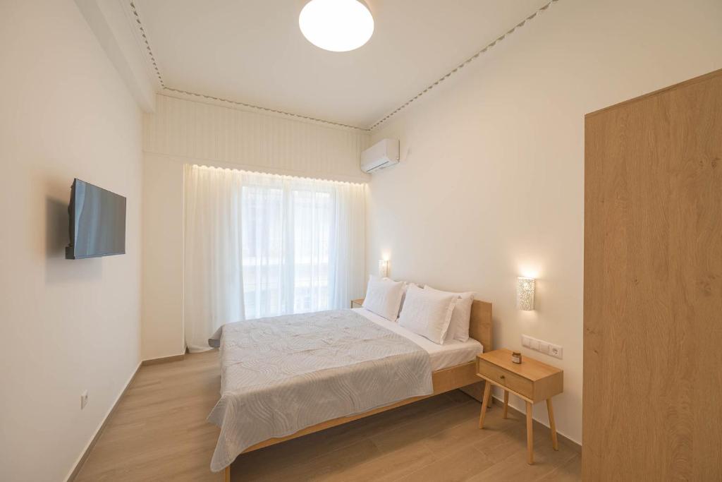 a white bedroom with a bed and a window at Corali 1 - Coastal Retreat in Katakolo