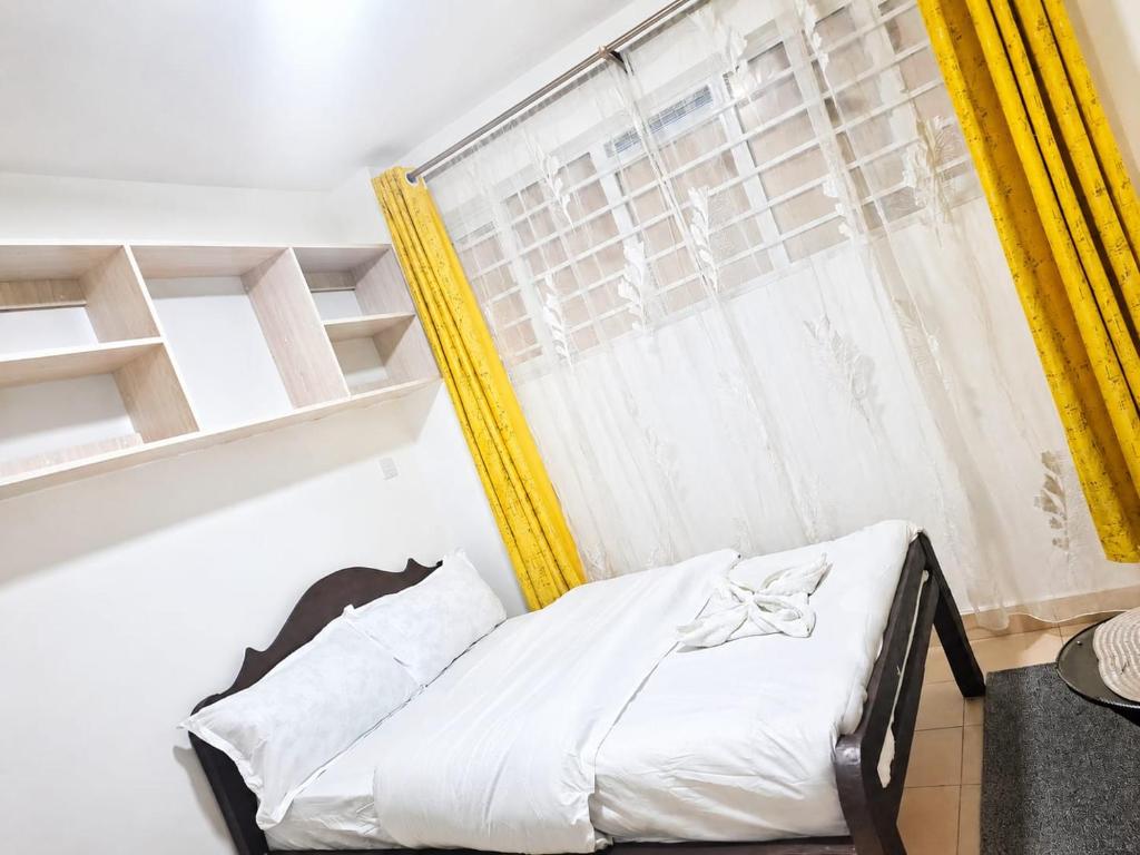 a bedroom with a bed and a window with yellow curtains at Phonex haven near Westside Mall in Nakuru