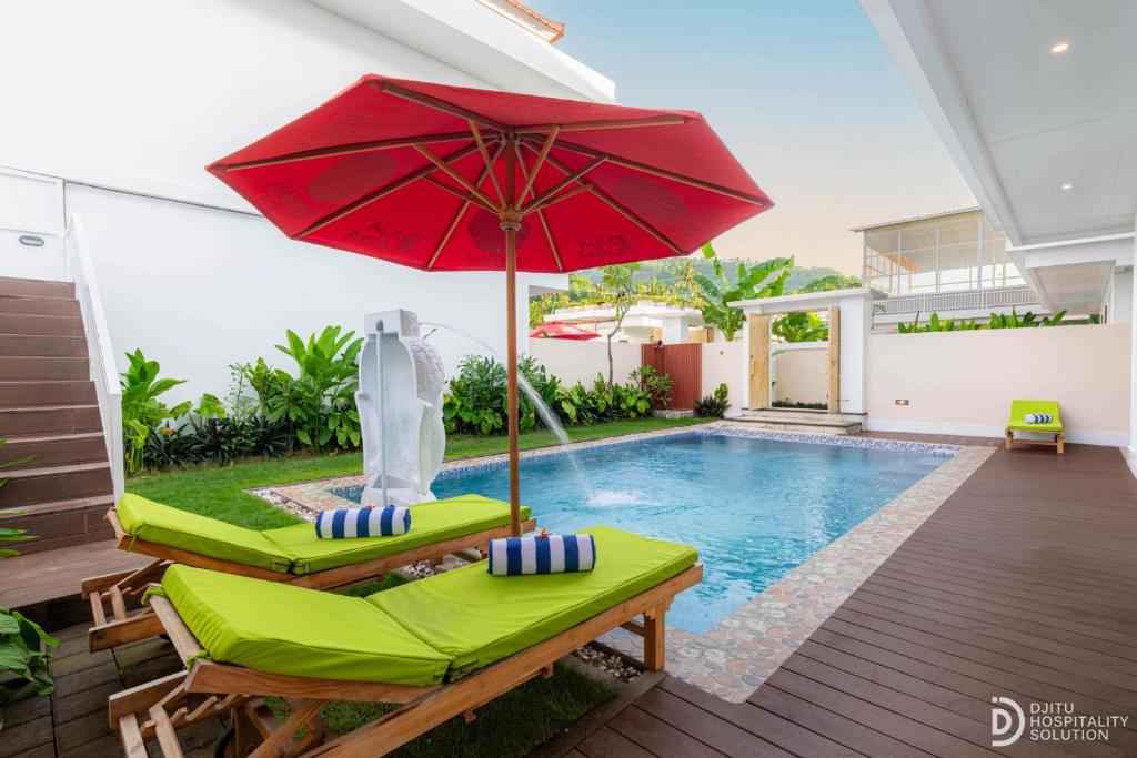 a pool with two chairs and a red umbrella at Made's Dream Villa Amed in Amed