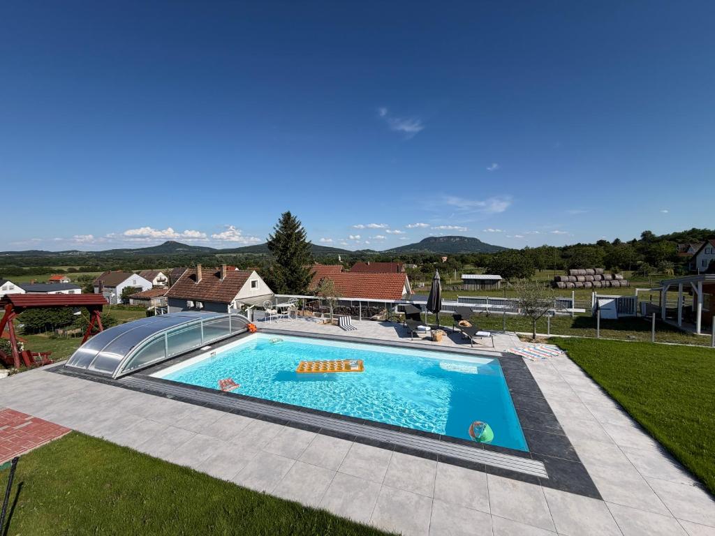 a swimming pool with a view of a house at Dandelion Vendégházak in Kisapáti