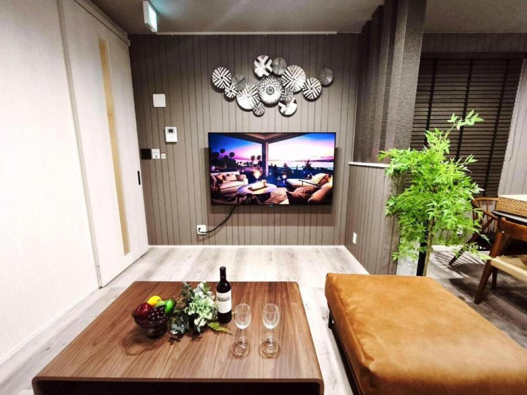 a living room with a table and a tv on a wall at HOTEL StayLuck KOTOHIRA - 琴平駅徒歩4分 in Kotohira