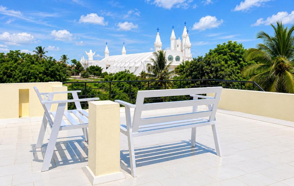 two white chairs sitting on a balcony in front of a mosque at Velānganni Vinodth Homestay in Velankanni