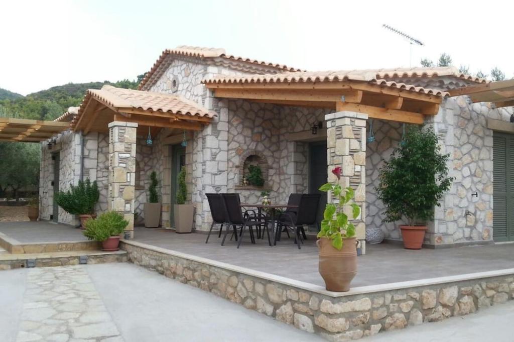 a stone house with a patio with a wooden pergola at Villa Lobos (Labrini) in Keri