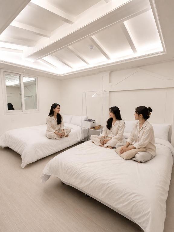 three women sitting on beds in a room at Olli Haus in Seoul