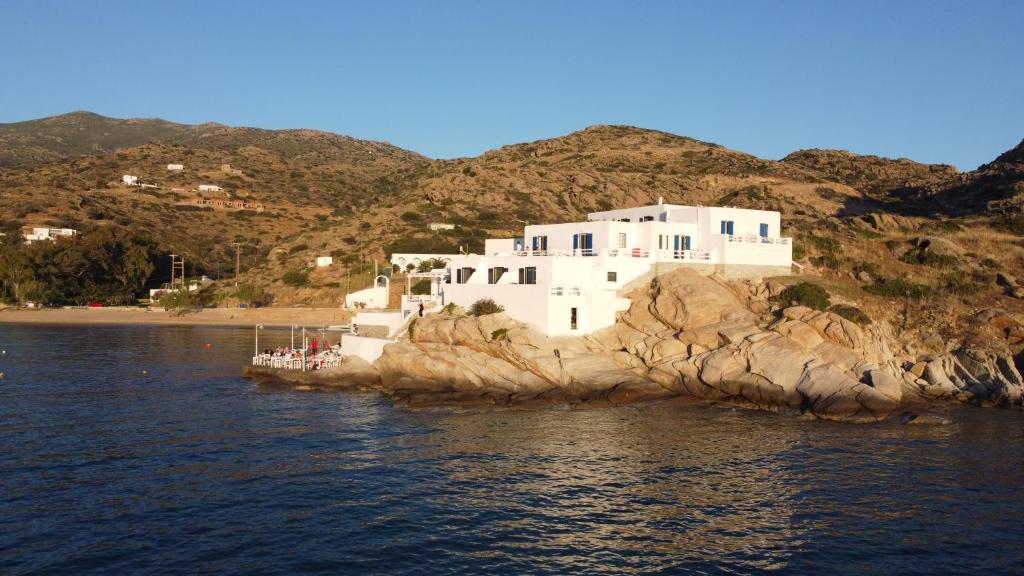 a large white house on a rocky island in the water at Psili Ammos in Mylopotas
