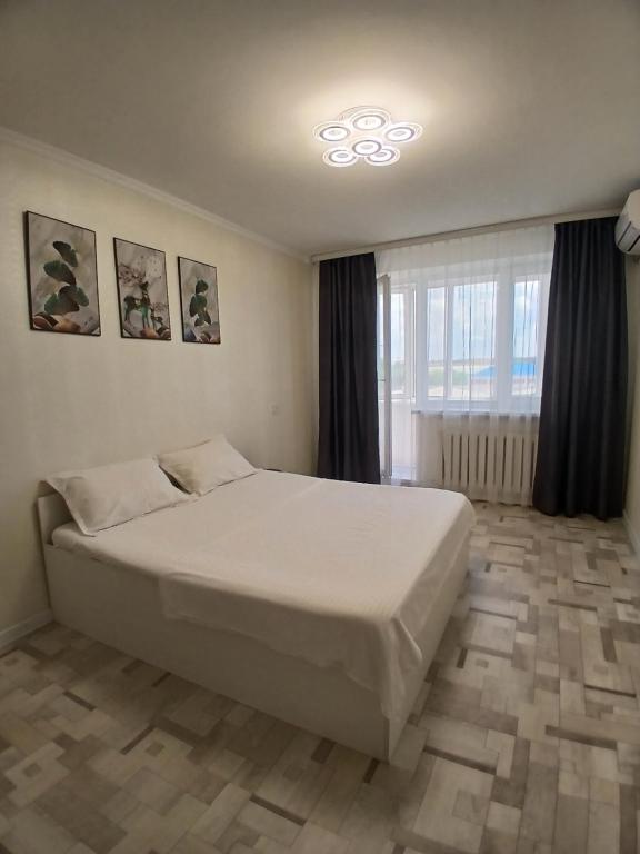 a bedroom with a white bed and a window at Циолковского с кодовым замком in Oral