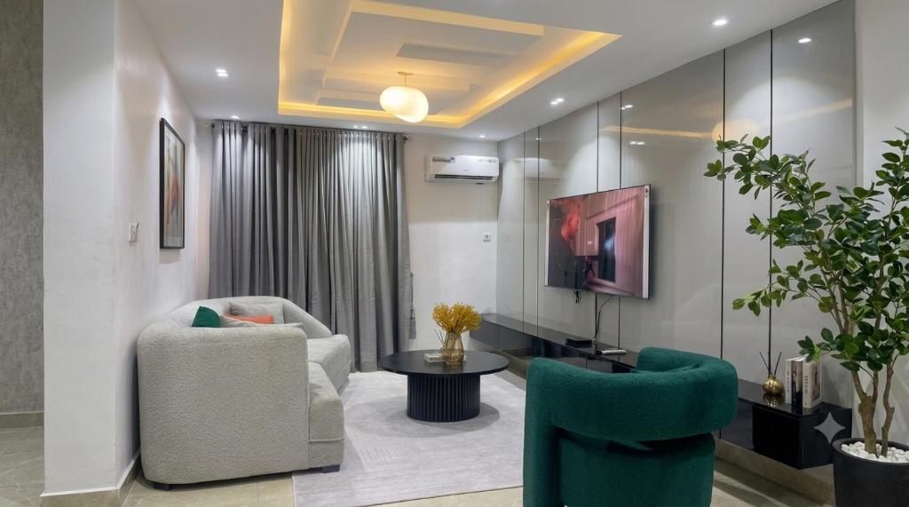 a living room with two chairs and a table and a tv at Three bedroom apartment Magodo GRA in Magodo