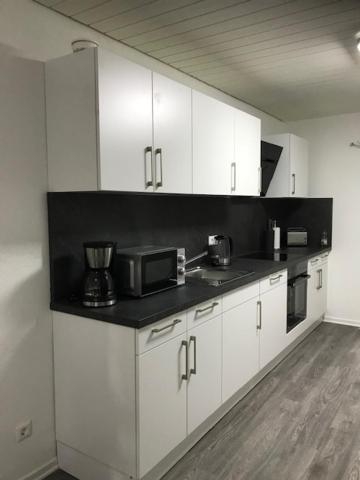 a kitchen with white cabinets and a black counter top at H4 Erdgeschoss in Nellingen