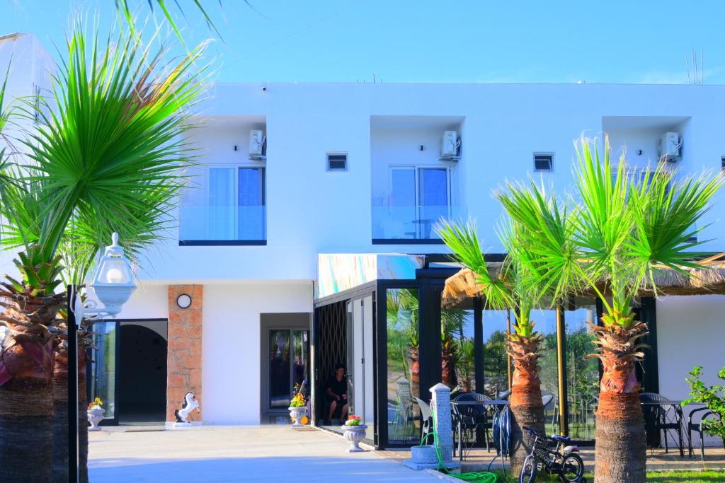a building with palm trees in front of it at Vila Bashkim in Ksamil