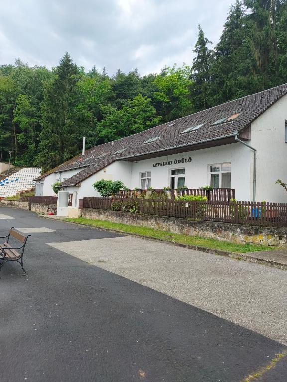 a white building with a bench in front of it at Leveleki Eszter Üdülő in Bánk
