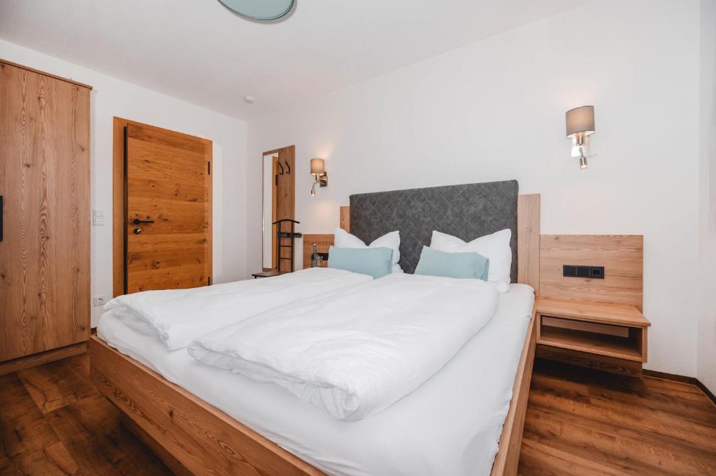 a bedroom with a large bed with white sheets and blue pillows at Doppelzimmer Deutschmann in Sankt Johann im Pongau