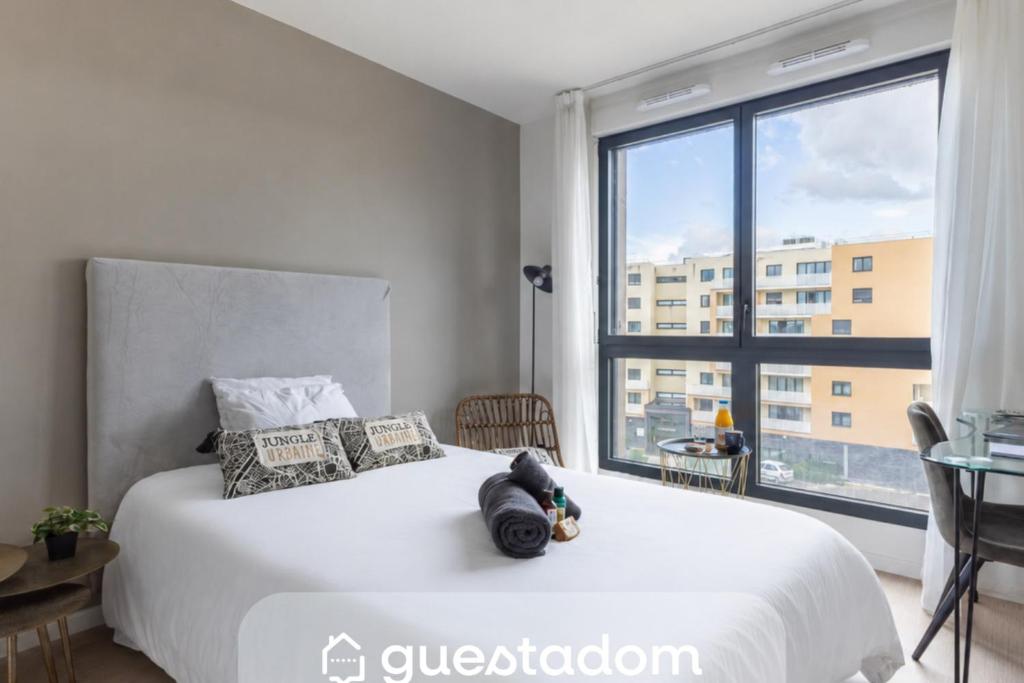 a bedroom with a white bed with a large window at 108 - L'Obsidienne - Wifi in Achères