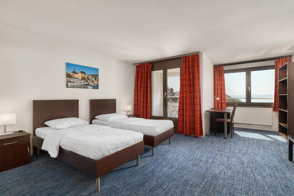 a hotel room with two beds and a desk at Neuchâtel City Hôtel - Self Check-In in Neuchâtel