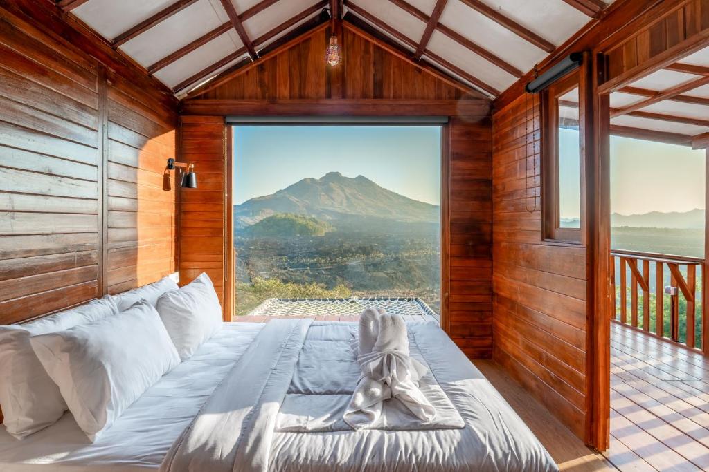 a bed in a room with a view of a mountain at Kamani Cabin by Moria in Kubupenlokan
