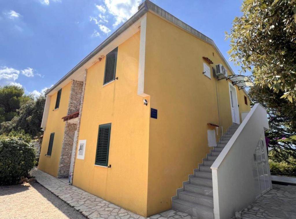a yellow building with a staircase in front of it at Apartments Vicelić in Lovište