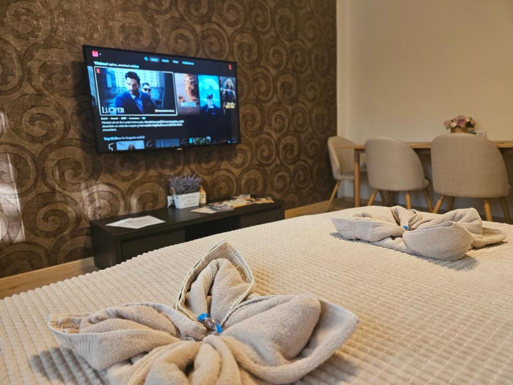 a hotel room with towels on a bed with a tv at Borisz Apartman in Makó