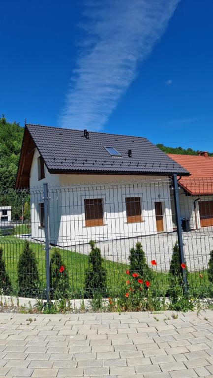a white house with a fence in front of it at Domek Pod Klimczokiem in Bystra