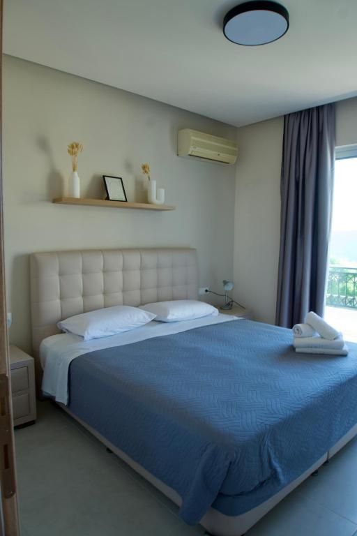 a bedroom with a large blue bed with a window at Johnhara Studios & Apartments in Ialysos