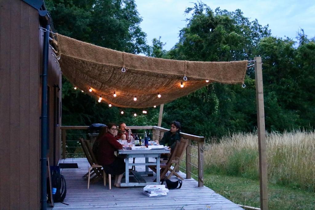 a group of people sitting at a table under a canopy at Tiny House Les Jours Heureux Sejour nature pres de Dinant et des Lacs de l Eau d Heure in Villers-le-Gambon
