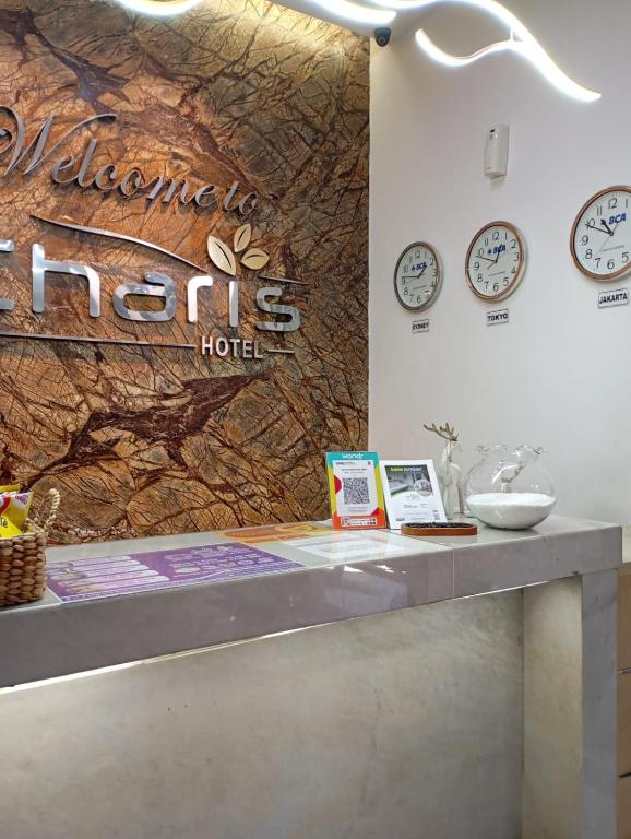 a reception counter with clocks on the wall at De La Charis Hotel in Kediri