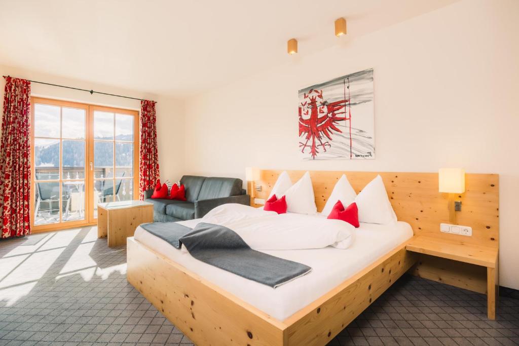 a bedroom with a large bed and a couch at Hotel Garni Frommes in Fiss