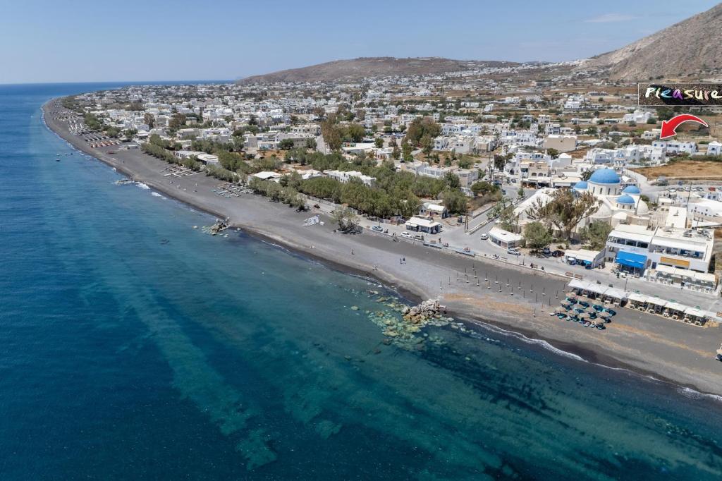 an aerial view of a beach with buildings and the ocean at Hotel Pleasure Blackbeach Santorini in Perissa