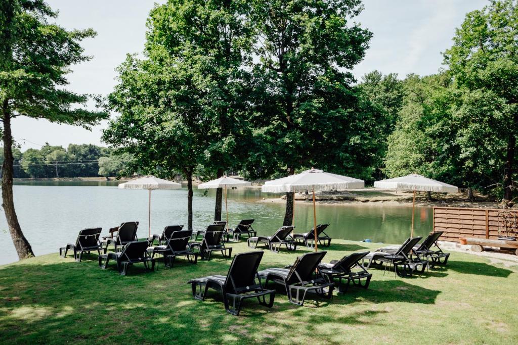 a group of chairs and umbrellas next to a lake at Penzión Topky in Banská Štiavnica