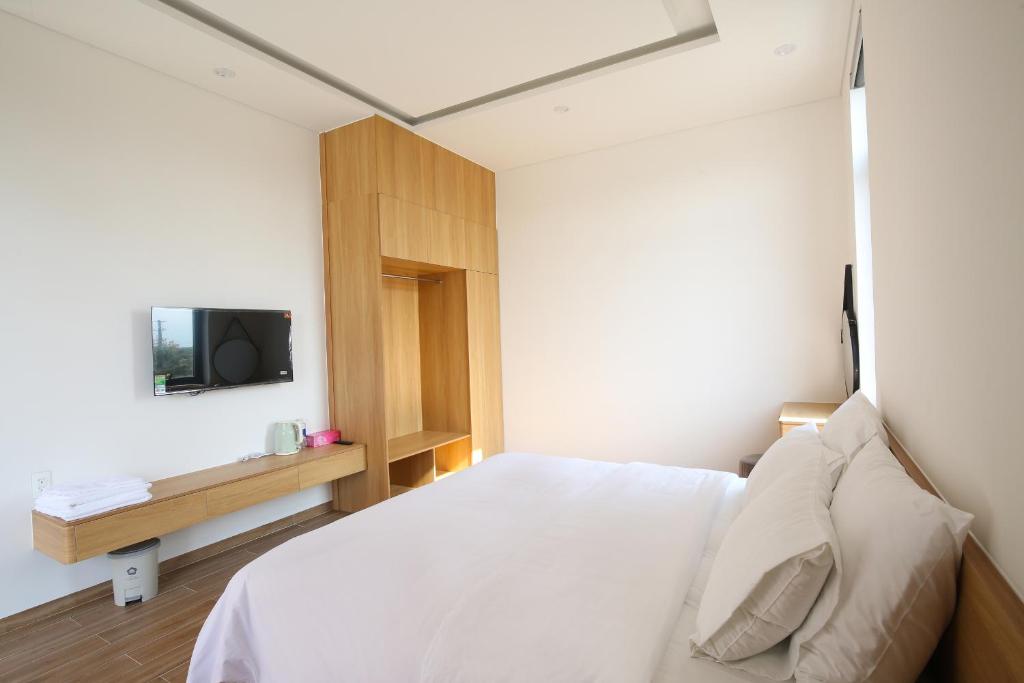 a bedroom with a bed and a tv on a wall at Cloud Rose Villa Hoi An in Danang