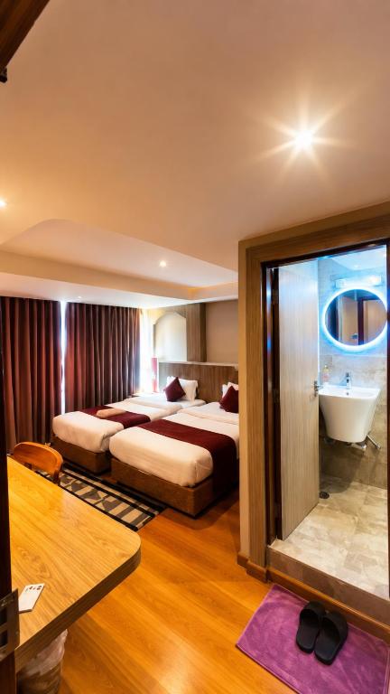 ein Hotelzimmer mit zwei Betten und einer Badewanne in der Unterkunft Hotel Yambu kathmandu in Kathmandu