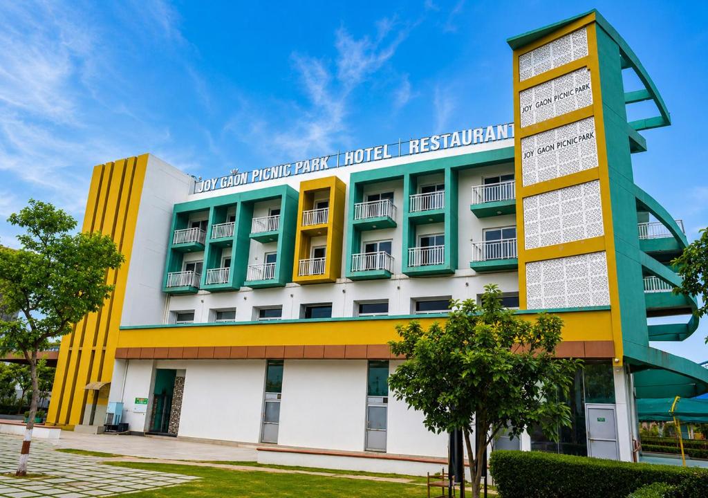a hotel with a yellow and white building at Joygaon Hotel & Resorts in Jhajjar