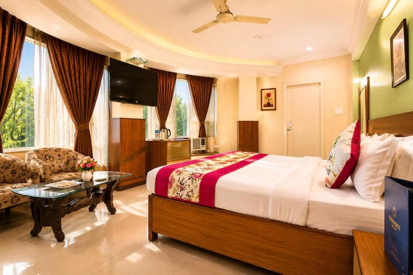 a hotel room with a large bed and a couch at Hotel Sunbeam in Gwalior