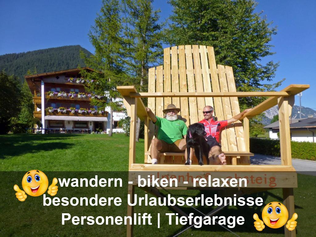 two men and a dog sitting in a giant chair at Alpenhof Wohlfühlpension in Obsteig