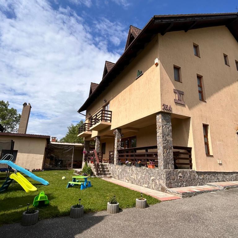 a house with a playground in front of it at Vila dintre Brazi in Moieciu de Jos